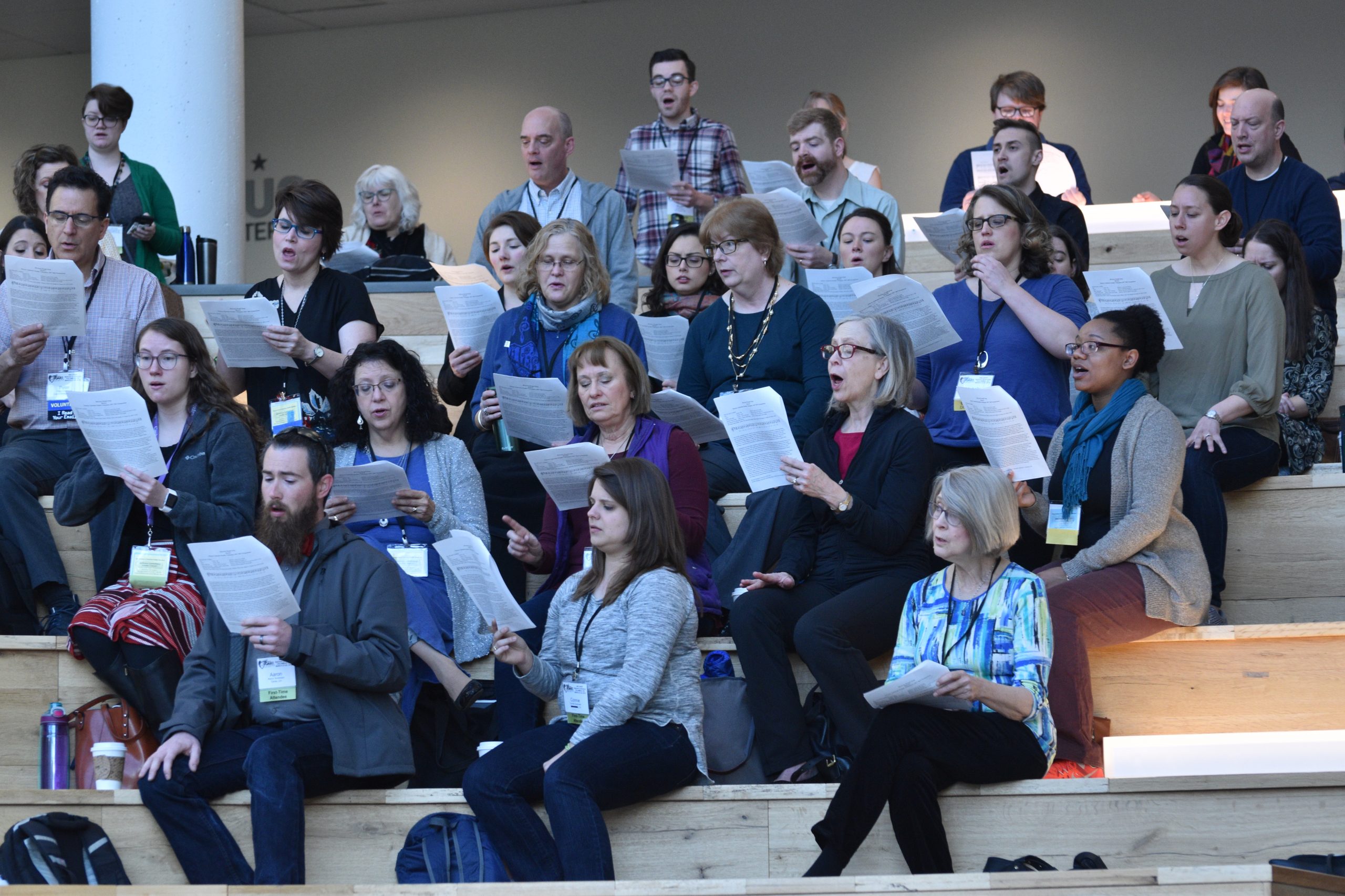 A picture of various conference attendees singing from sheet music 